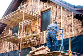 Handwerker auf dem Baugerüst vor einer gedämmten Fassade.