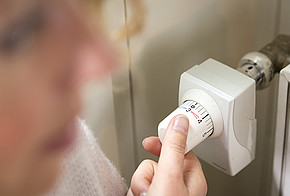 Frau dreht Thermostat herunter auf 3