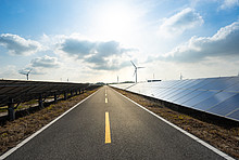 Windräder und Solaranlagen an einer Straße.