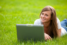 Frau mit Laptop auf Wiese