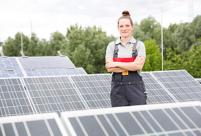 Installateurin zwischen Solarmodulen