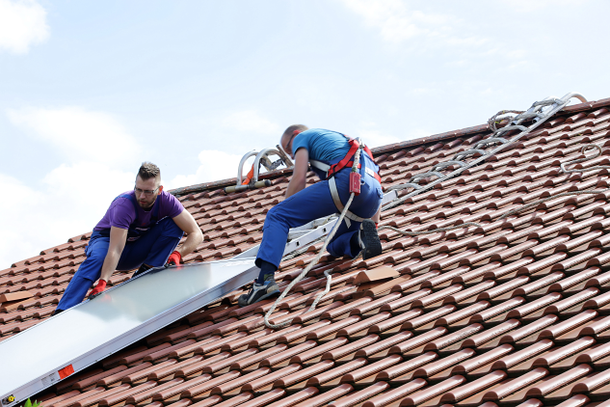 Installation Solarthermie: Männer schieben Kollektor übers Dach