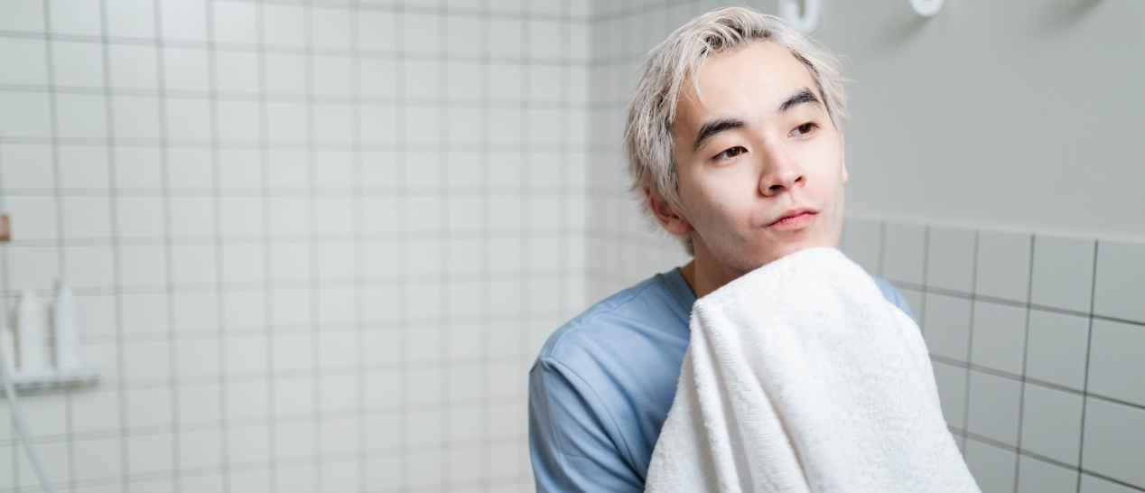 Mann im Badezimmer beim Gesichtabtrocknen